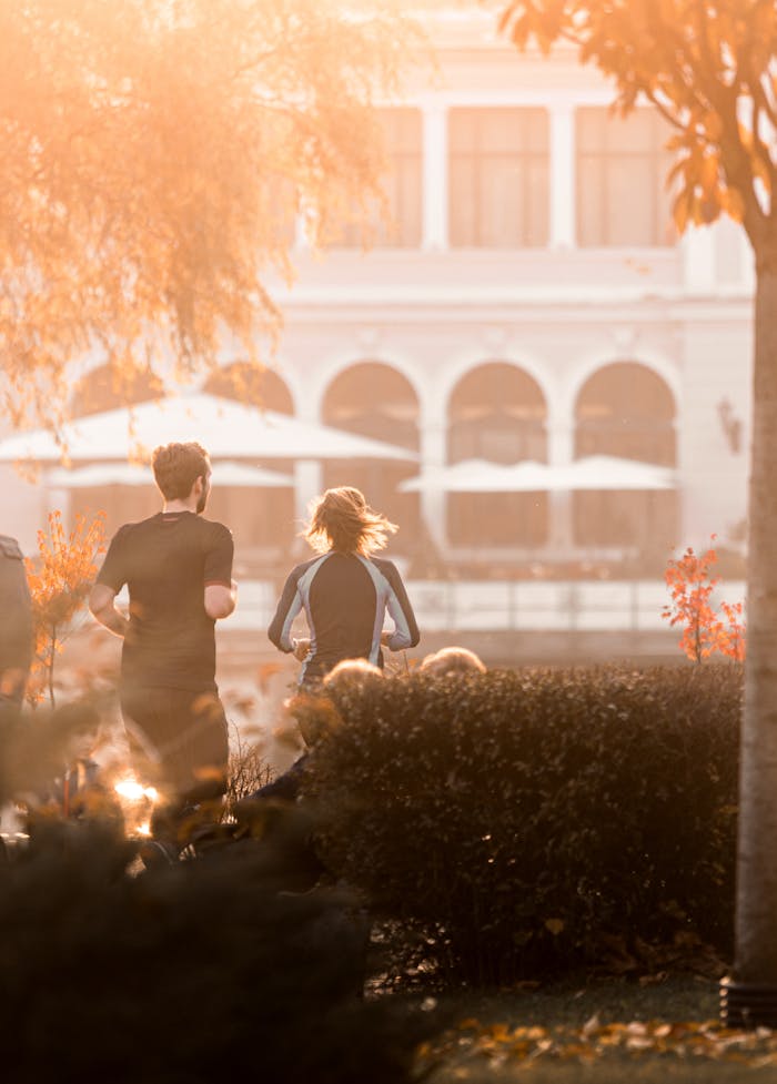 A couple jogging in a sunlit park, enjoying a refreshing morning run.